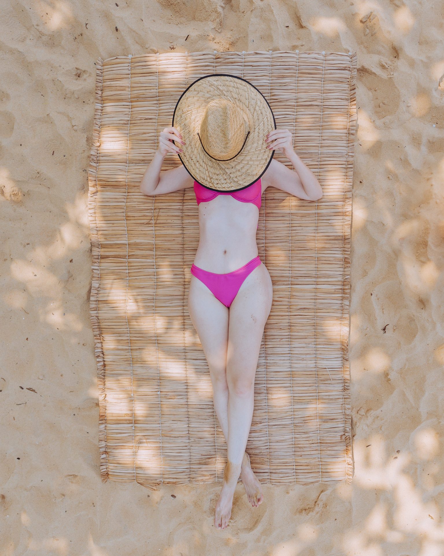 A Woman in Pink Bikini Covering Her Face with a Hat