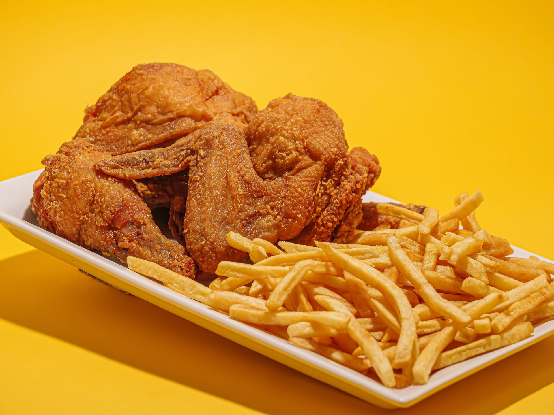 Friend chicken and French fries in yellow background